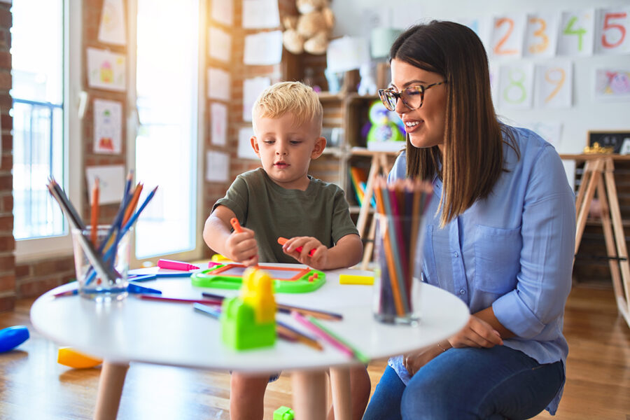 A child care provider smiling with a young child, symbolizing confidence and success after setting child care rates that support quality care.