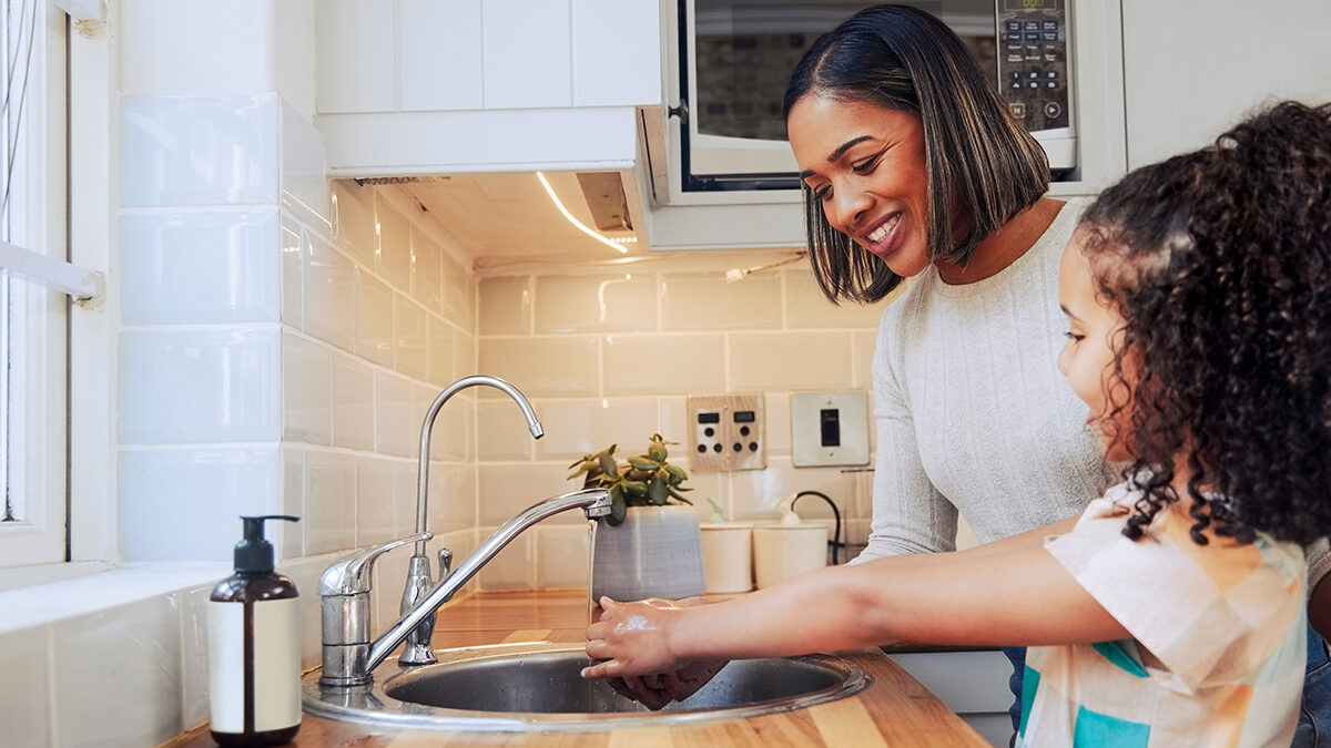 Mom helping her young daughter wash her hands is a good health guideline to follow