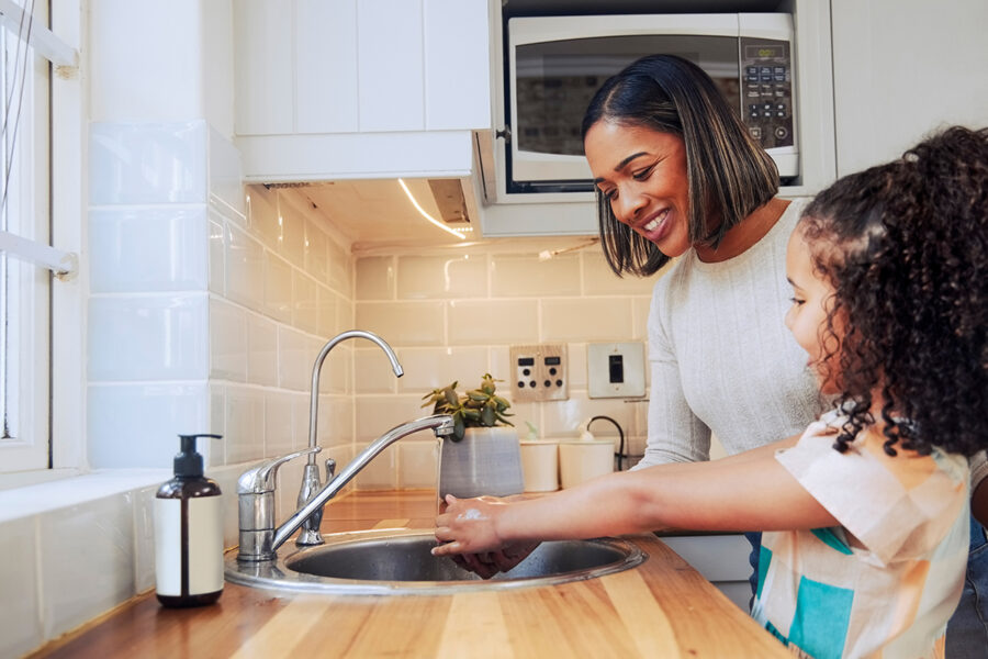 Mom helping her young daughter wash her hands is a good health guideline to follow