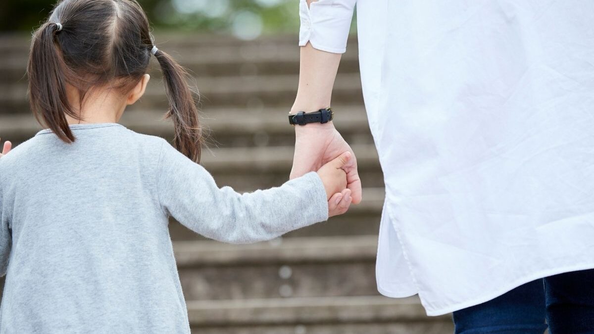 Parent and child holding hands while walking up steps, symbolizing support and guidance in applying for subsidized child care in Sacramento.