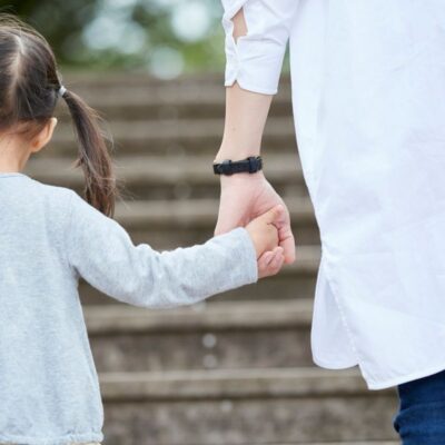 Parent and child holding hands while walking up steps, symbolizing support and guidance in applying for subsidized child care in Sacramento.