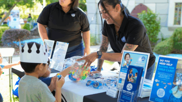 Child Action staff smiling and sharing resources with a young boy and his family