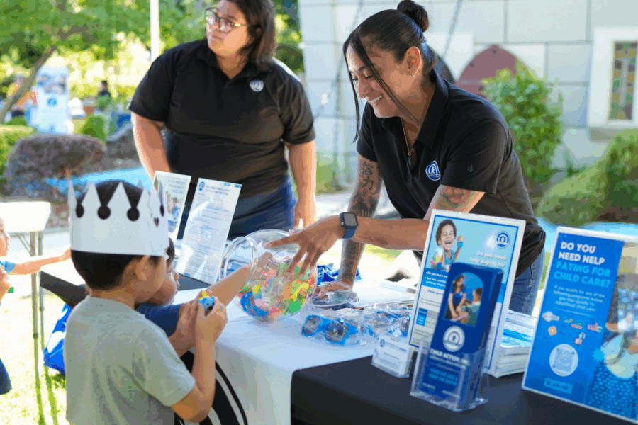 Child Action staff smiling and sharing resources with a young boy and his family