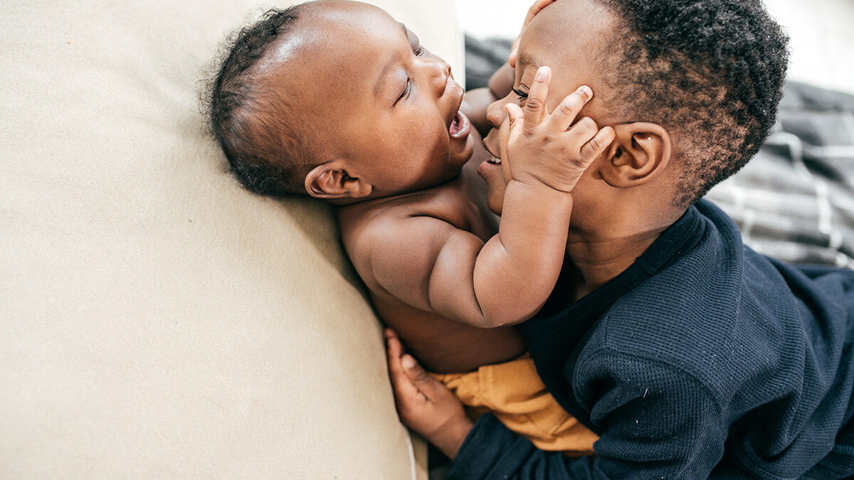 Toddler and infant playing together in a caring, supportive environment.”