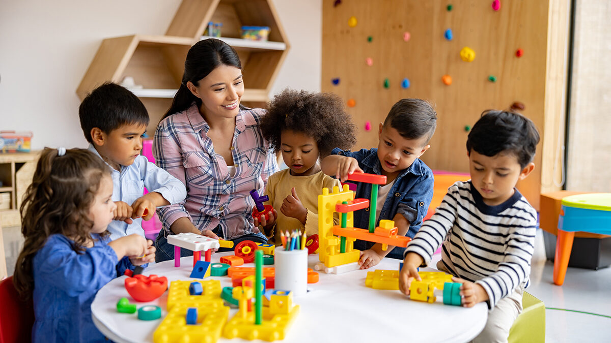 A child care provider engaging with a diverse group of young children in a classroom, representing Child Action’s mission to help families find a provider they can trust.
