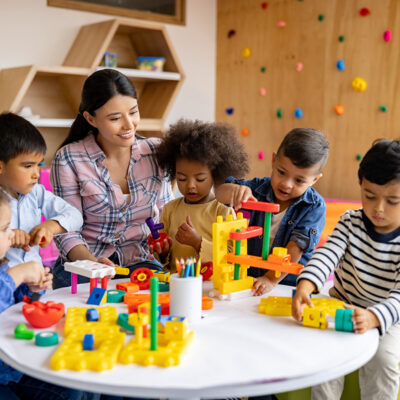 A child care provider engaging with a diverse group of young children in a classroom, representing Child Action’s mission to help families find a provider they can trust.